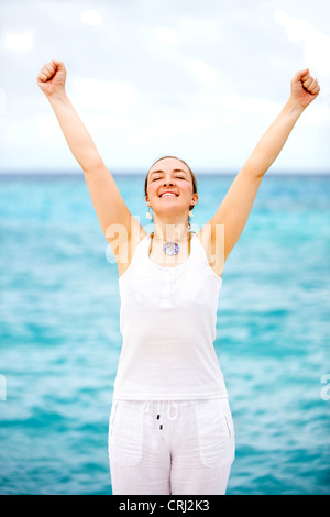 Felice donna in piedi con le braccia tese in spiaggia Foto Stock