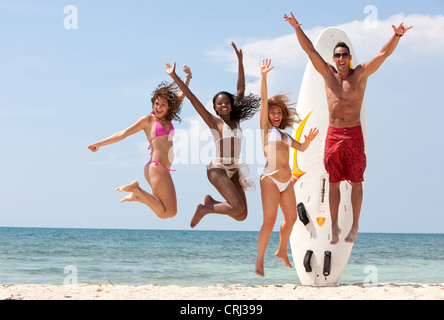 Felice gruppo di amici jumping pieno di gioia per la spiaggia Foto Stock