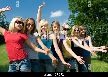 Un gruppo di ragazze adolescenti che pongono in un prato in fila uno dietro l altro Foto Stock