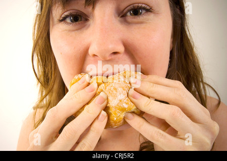 Una giovane donna jam donut junkie. Jam Donut hanno criticato dal cibo spazzatura gli attivisti in guerra globale sull'obesità come insalubre con scarso valore nutrizionale. Il termine "junk food" è stato coniato da Michael Jacobson, direttore del Centro per la scienza nel pubblico interesse, per descrivere il cibo che conteneva contengono livelli elevati di grassi saturi, sale o zucchero e Foto Stock