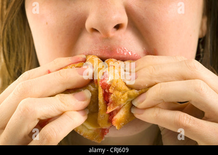 Una giovane donna jam donut junkie. Jam Donut hanno criticato dal cibo spazzatura gli attivisti in guerra globale sull'obesità come insalubre con scarso valore nutrizionale. Il termine "junk food" è stato coniato da Michael Jacobson, direttore del Centro per la scienza nel pubblico interesse, per descrivere il cibo che conteneva contengono livelli elevati di grassi saturi, sale o zucchero e Foto Stock