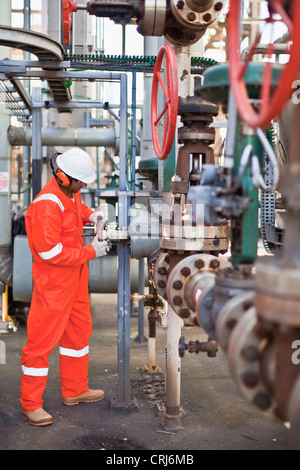 Lavoratore manometro di regolazione alla raffineria di petrolio Foto Stock