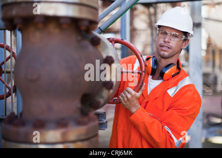 Lavoratore manometro di regolazione alla raffineria di petrolio Foto Stock