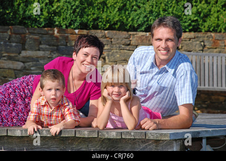 Giovane famiglia con due bambini che giace sul Boardwalk Foto Stock