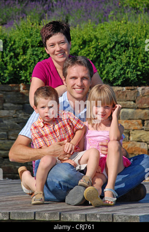 Giovane famiglia con due bambini seduti sul Boardwalk Foto Stock