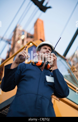 Lavoratore utilizzando walkie talkie sul sito Foto Stock