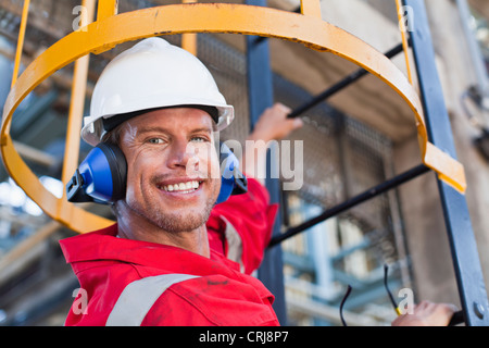 Lavoratore scaletta di arrampicata alla raffineria di petrolio Foto Stock