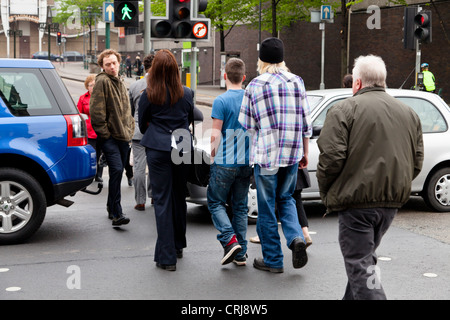 Blocca il traffico attraverso un passaggio pedonale su una strada mentre il verde luce uomo mostra, causando la gente a piedi tra le vetture. Nottingham, Inghilterra, Regno Unito Foto Stock