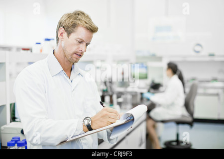 Scienziato sulla scrittura di appunti di laboratorio Foto Stock