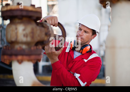 Lavoratore regolare il manometro a impianto chimico Foto Stock