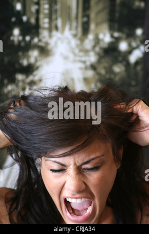 Giovane donna urlando e strappando i suoi lunghi capelli castani Foto Stock