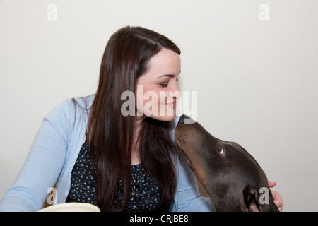 Giovane donna rendendo kissy faccia con Dobermann cane. Foto Stock