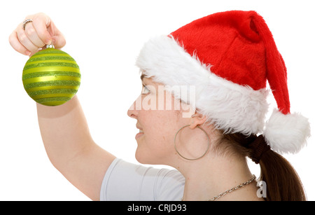 Bella ragazza che indossa un cappello di Natale guardando un albero di Natale sfera Foto Stock