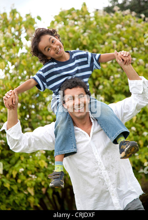 Padre dando un piggyback ride a suo figlio all'aperto Foto Stock