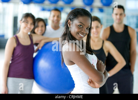 Nero donna sorridente con un gruppo di persone di palestra sullo sfondo Foto Stock