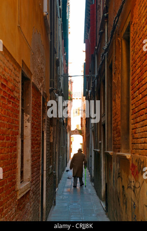 Il vecchio uomo che cammina attraverso uno stretto vicolo a Venezia, Italia, Venezia Foto Stock