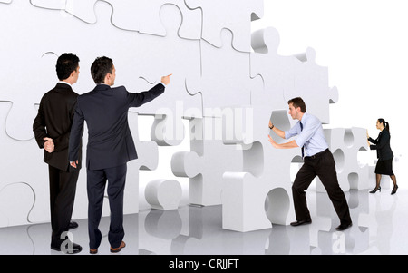 Young business Team building una parete gigante di pezzi di un puzzle Foto Stock