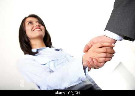 Young business woman agitando una mano maschio con un sorriso Foto Stock