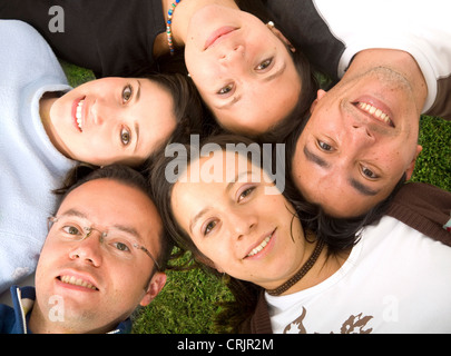 Gruppo di amici divertendosi giacente con le loro teste insieme in un prato Foto Stock