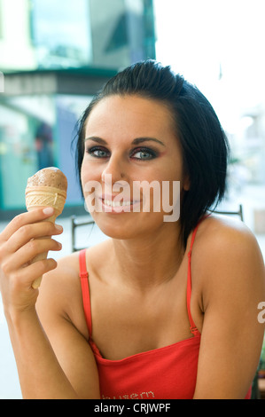 Giovane donna in abiti estivi a mangiare il gelato Foto Stock