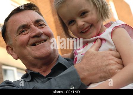 Un uomo anziano porta un bambino sulla sua spalla. Foto Stock