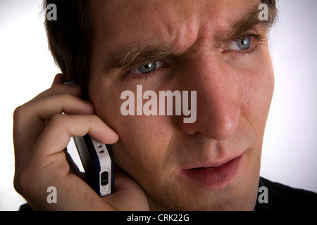 Un preoccupato per il giovane uomo a parlare su un telefono cellulare. Foto Stock