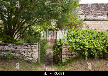 Cottage in pietra di Cotswold con cancello aperto in muro di pietra, Kelmscott, Oxfordshire occidentale, Inghilterra, Regno Unito Foto Stock