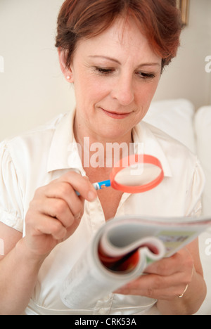 Donna di lettura con lente di ingrandimento Foto Stock