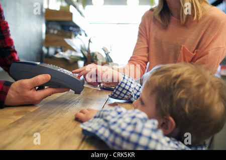 Boy utilizzando la macchina per le carte di credito in negozio Foto Stock