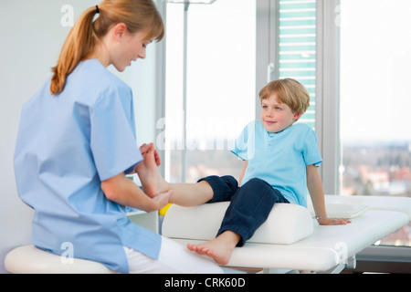 Medico di esaminare i ragazzi in piedi in ufficio Foto Stock