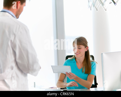 Medico parlando a receptionist in office Foto Stock