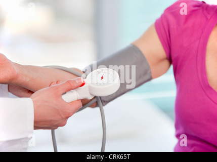 Medico tenendo womans pressione sanguigna Foto Stock