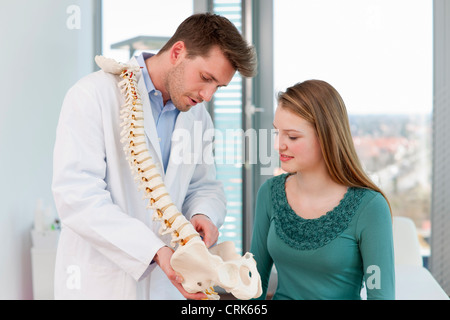 Medico che mostra il modello della colonna vertebrale per il paziente Foto Stock