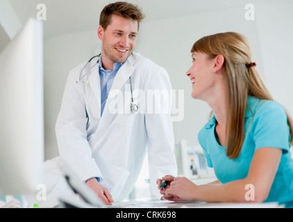 Medico parlando a receptionist in office Foto Stock