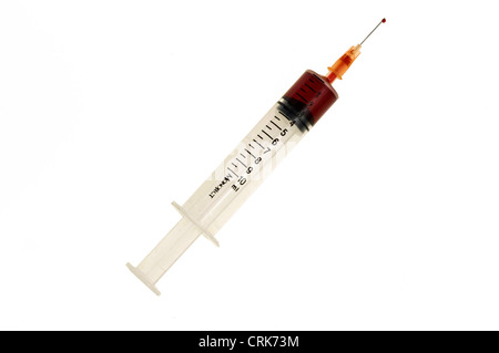 Vista di un ago fissato ad una siringa, la punta dell'ago contiene una gocciolina di liquido. Foto Stock