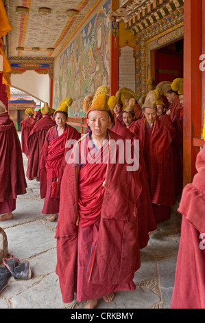 Monaci buddisti tibetani (Geluk o cappello giallo) lasciando il Sutra del Grand Hall del monastero di Labrang a Xiahe dopo la preghiera. Foto Stock