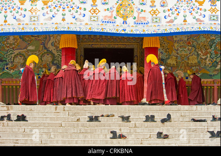 Monaci buddisti tibetani (Geluk o cappello giallo) immettere il Sutra del Grand Hall del monastero di Labrang a Xiahe a pregare. Foto Stock