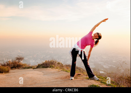 Donna stiramento sulla collina Foto Stock