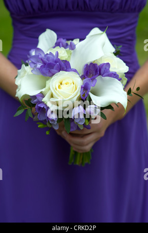 Una damigella in viola tenendo un mazzo di nozze Foto Stock