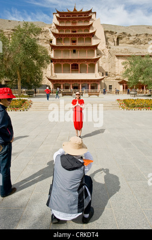 I turisti scattano fotografie al di fuori grotta 96 (aka nove piani) probabilmente la più famosa delle grotte di Mogao. Foto Stock