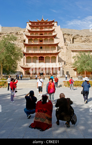 I turisti scattano fotografie al di fuori grotta 96 (aka nove piani) probabilmente la più famosa delle grotte di Mogao. Foto Stock