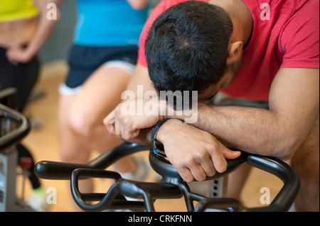 Uomo appoggiato sulla macchina di spin in palestra Foto Stock