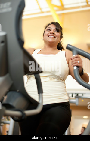 Donna che utilizza macchina ellittica in palestra Foto Stock