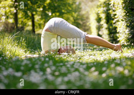 Una giovane donna a praticare yoga al di fuori, aratro pongono Foto Stock