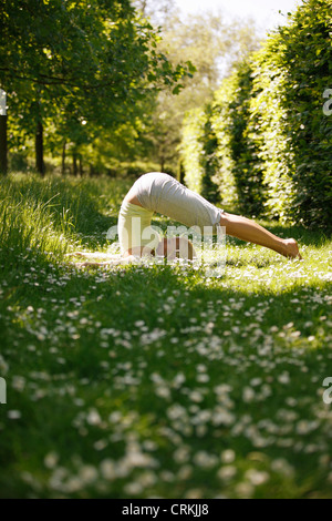 Una giovane donna a praticare yoga al di fuori, aratro pongono Foto Stock