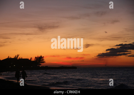 Tramonto a Varadero sulla costa settentrionale di Cuba, la gente camminare sulla spiaggia la visualizzazione di cielo rosso sopra il livello del mare Foto Stock