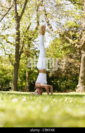 Una giovane donna facendo un headstand al di fuori Foto Stock