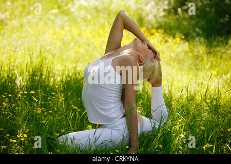 Una giovane donna a praticare yoga al di fuori, piccione pongono close up Foto Stock