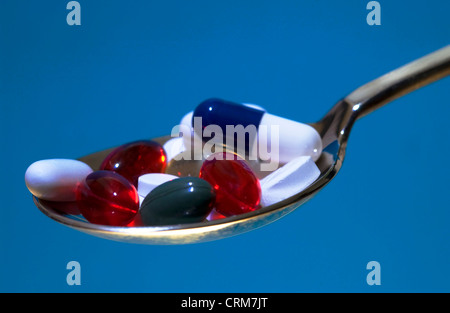 Un cucchiaio di colori assortiti pillole e capsule. Foto Stock