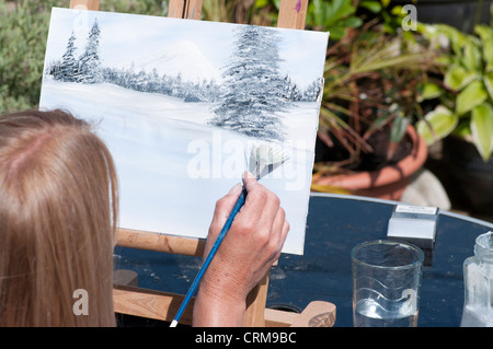 Persona artista pittura con spazzola di vernice su una tela su un cavalletto Foto Stock